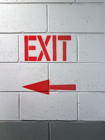 Exit text sign. Arrow red pointer exit. Emergency exit from building, wall texture.