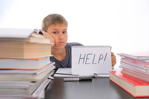istock Learning difficulties, school, quarantine education concept. Tired frustrated boy sitting at table with many books. Word Help on open notebook. 1356940022
