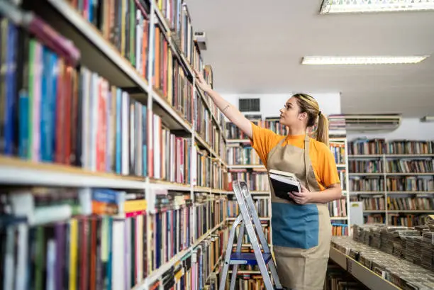 Bookseller arranging books in a shelf