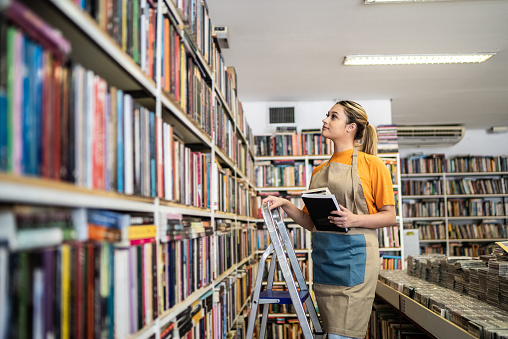 Bookseller arranging books in a shelf