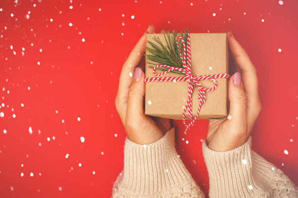 istock Christmas gift in women's hands on a red background 1356943902
