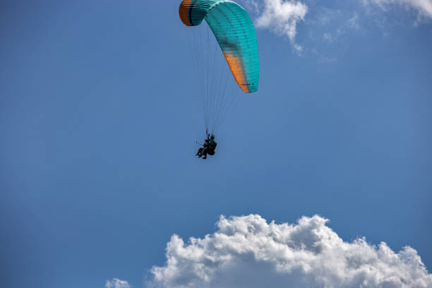 istock Paragliding with a pair of instructors. Bright blue sky with beautiful white fluffy clouds. 1356946428