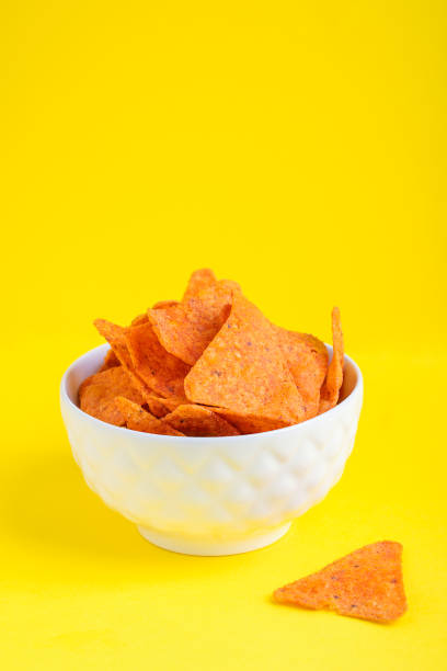 istock Mexican Nachos crispy fried corn tortilla chips served in white bowl against yellow background 1356947824