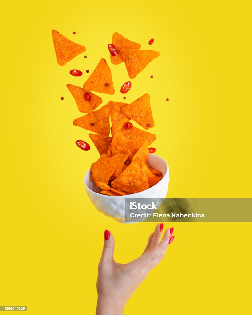 Levitation of hot Nachos mexican crispy fried tortilla chips with chili pepper slices served in white bowl with woman palm against yellow background Levitation or flying of spicy hot Nachos mexican crispy crunchy tortilla chips with slices of chili pepper served as appetizer in white bowl with woman hand or palm isolated against yellow background Nacho Chip Stock Photo