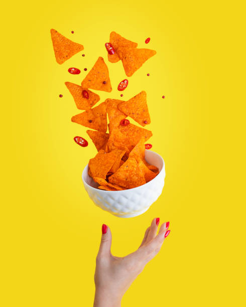 Levitation of hot Nachos mexican crispy fried tortilla chips with chili pepper slices served in white bowl with woman palm against yellow background Levitation or flying of spicy hot Nachos mexican crispy crunchy tortilla chips with slices of chili pepper served as appetizer in white bowl with woman hand or palm isolated against yellow background nachos stock pictures, royalty-free photos & images