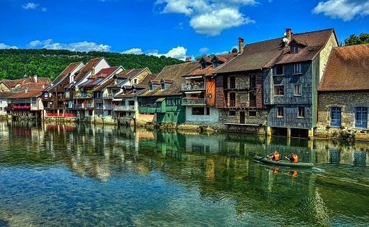 Canoe navigation along the Loue river which is overlooked by the characteristic houses. Town of Ornans in the Doubs department, Burgundy-Franche-Comte region, France. HDR image
