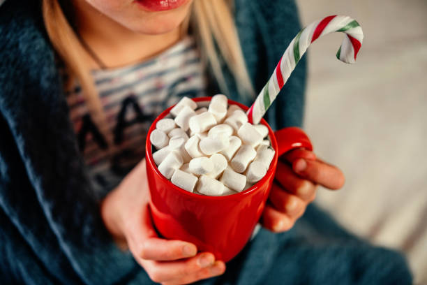 istock Hands holding a red cup of hot chocolate with marshmallows Christmas background 1356949841