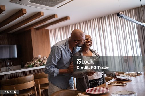 istock Mature couple setting the table for lunch or dinner at home 1356951171