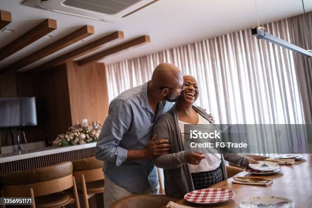 Mature Couple Setting The Table For Lunch Or Dinner At Home Stock Photo - Download Image Now