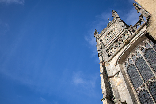 Looking up at the imposing  Church of St John the Baptist in the centre of Cirencester, in the Cotswolds on a bright sunny day