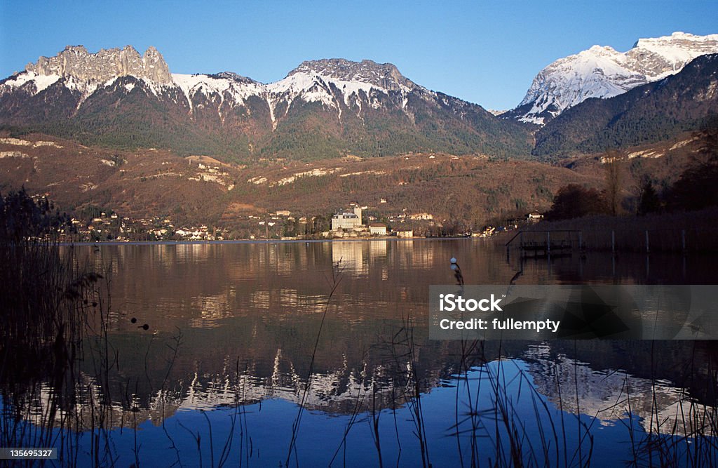 Snowed mountains and castle reflecting in lake Annecy Snowed mountains of Forclaz and Tournette, and castle of Duingt reflecting in lake Annecy, in winter. France Annecy Stock Photo