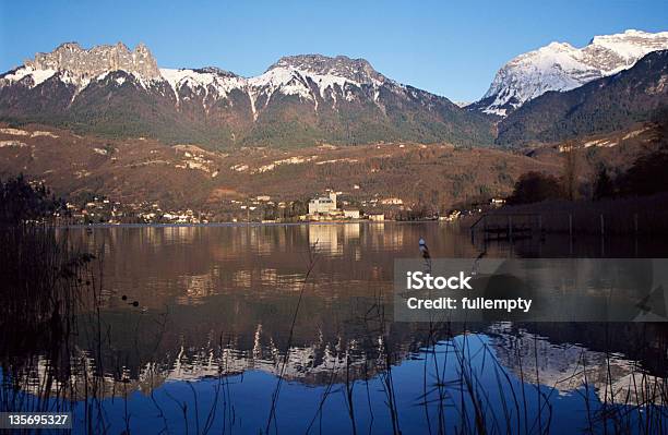 Snowed Mountains And Castle Reflecting In Lake Annecy Stock Photo - Download Image Now