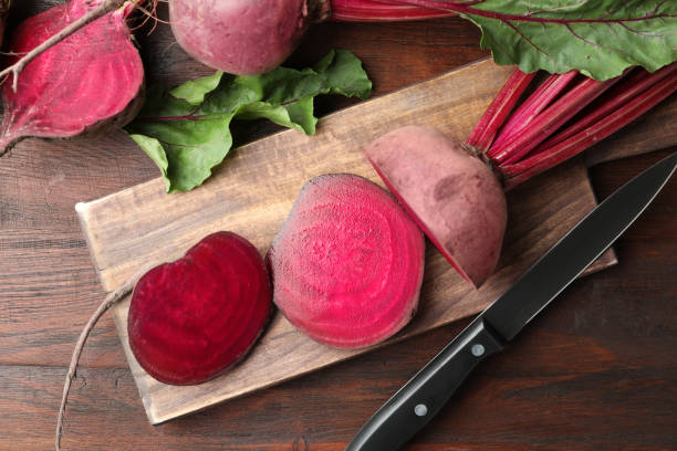 istock Cut raw beets and knife on wooden table, flat lay 1356954417