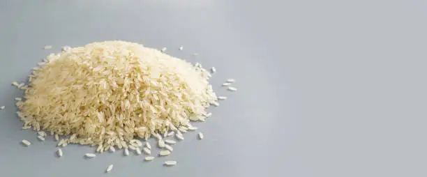 Photo of Baner. White milled long grain rice on a gray background. Vegan food concept. Rice dishes are cooked in all countries of the world. Popular cereal. Selective focus.