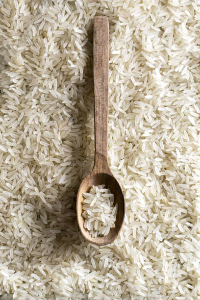 White long grain in wood spoon. Healthy food concept. Rice dishes are cooked in all countries of the world. Popular cereal. Top view stock photo