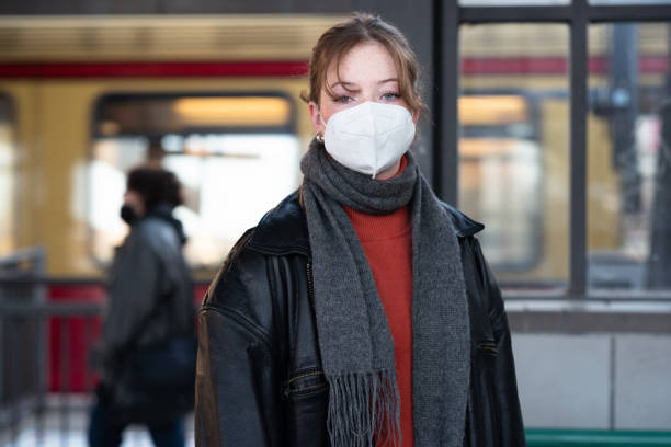 mädchen im teenageralter mit maske, das auf einem bahnsteig des bahnhofs steht - weiblicher teenager allein stock-fotos und bilder