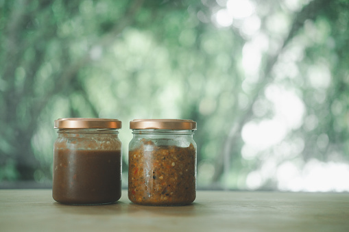 Two jars of Thai chili sauce with lid on table