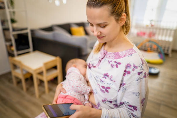 istock Young mother texting while her newborn baby is asleep 1356963140
