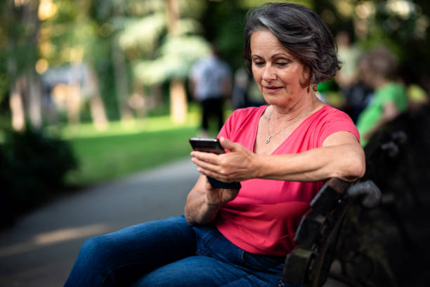 istock Senior woman using mobile phone in park. 1356963431