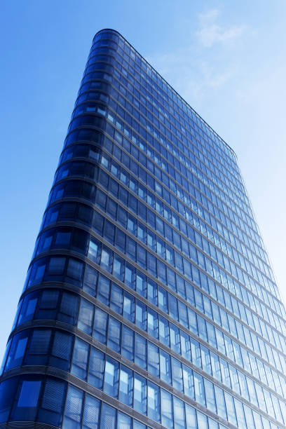 istock Tall office building with metal construction and windows reflecting the sky - low angle view - vertical 1356965873