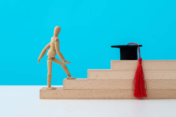 istock Wooden puppet climbing stairs to the mortarboard 1356966268