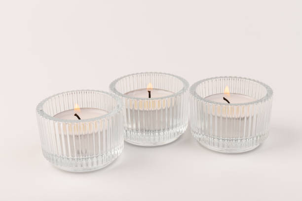 istock Burning tea candles in a glass holder, isolated on white. Space for text 1356972158