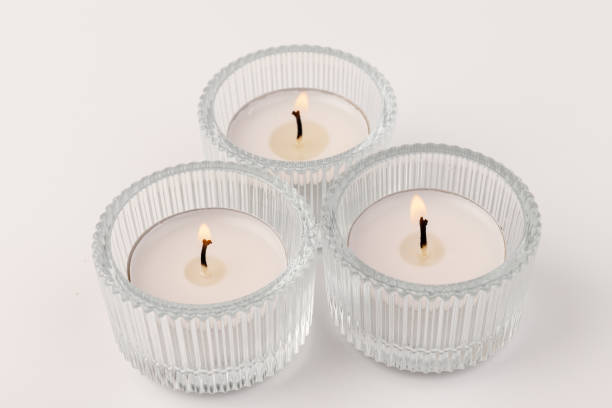 istock Burning tea candles in a glass holder, isolated on white. Space for text 1356972162
