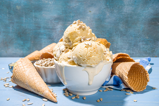 Homemade organic sunflower seeds ice cream, vegan non-allergic ice cream with sunflower seeds and waffle cones, on blue sunny wooden background copy space