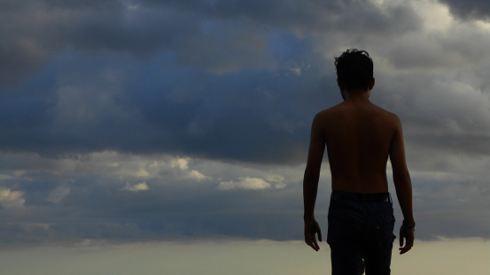 back view of a shirtless man against a foggy sky background