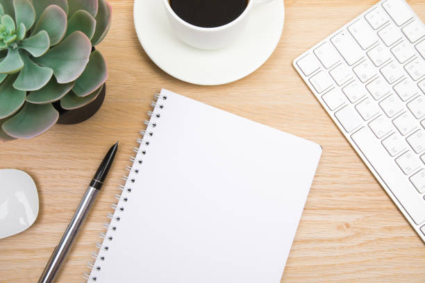 istock open notepad, cup of coffee, pen ,moose, keyboard on wooden background spiral notebook on table Business, planning, education, morning life working from home concept Top view Flat lay Mock up 1356980801