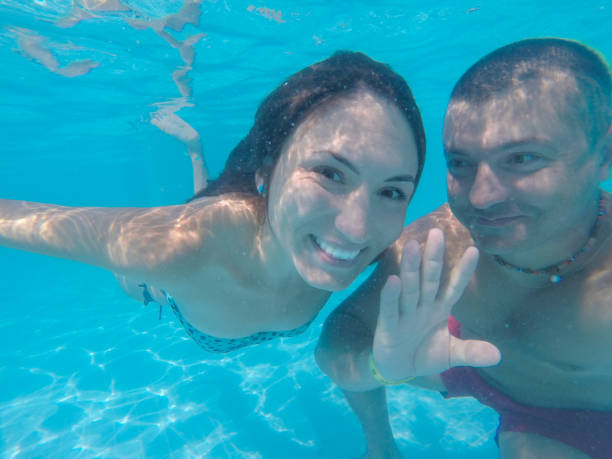 istock Happy couple smiling underwater in pool with blue water 1356981673