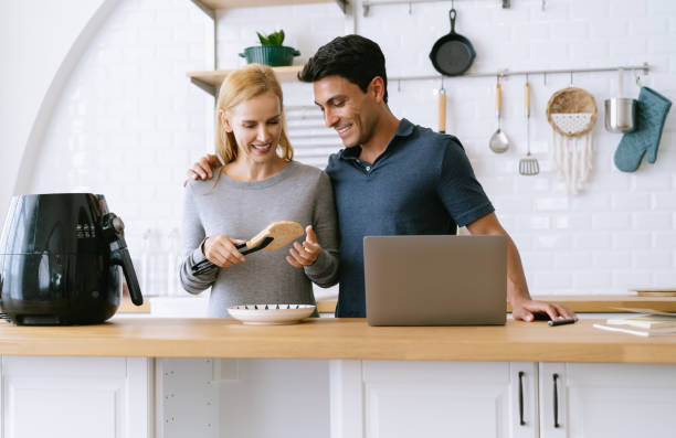istock Attractive middle aged couple on kitchen. Beautiful woman is coo 1356982105