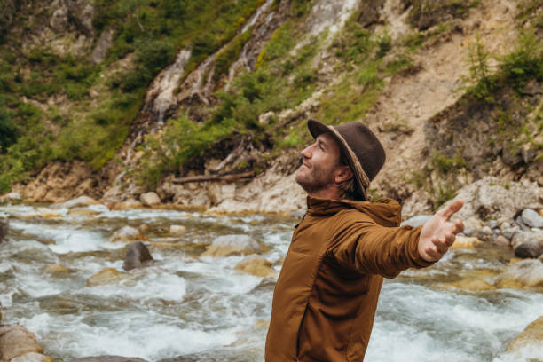 istock Man standing by the river arms wide open 1356983670