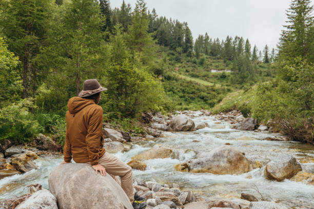 istock Young man by the river contemplating nature 1356983805