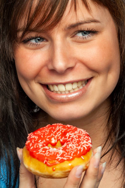 istock Donuts fun; Attractive Young Woman with one pink Iced Donuts 1356984334