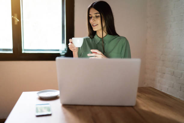 istock Young businesswoman drinking coffee, while working from the modern coffee shop 1356984476