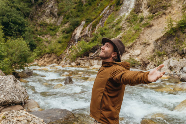 istock Man standing by the river arms wide open 1356985142