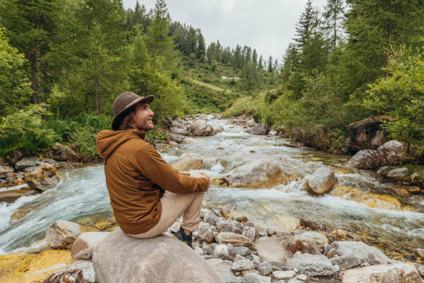 istock Young man by the river contemplating nature 1356986032