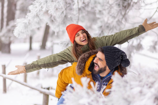 Boyfriend piggybacking girlfriend on snowy winter day stock photo