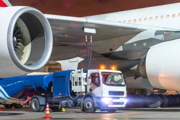 Truck with a tank of kerosene of aviation fuel connected to the fuel tanks of a large aircraft airliner, refueling service of a night flight