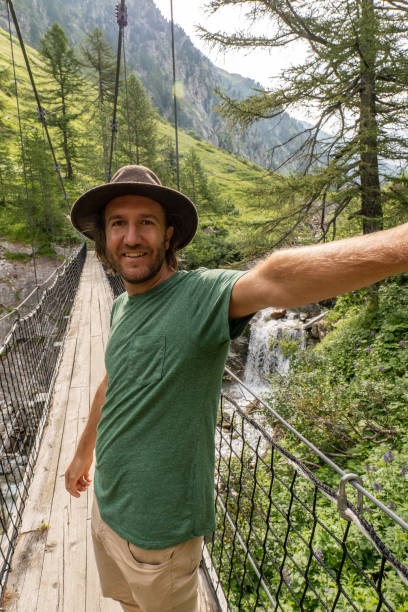 istock Young man takes selfies on hanging bridge during a hike 1356990774