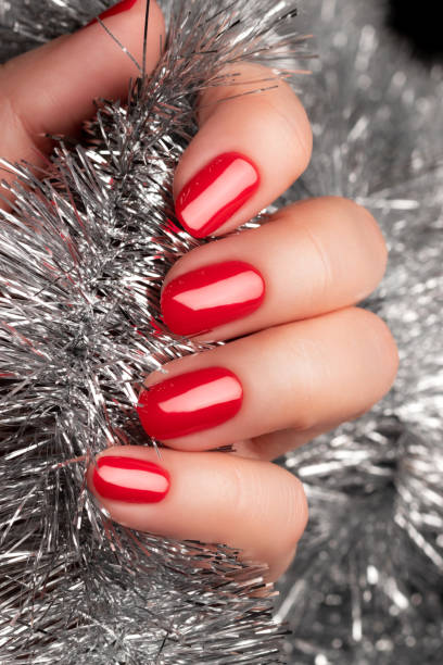 istock Hand with red nails with Christmas tinsel 1356992010