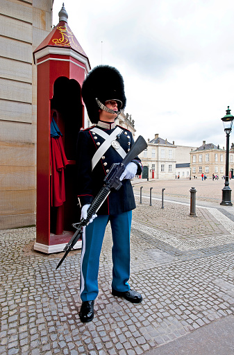 Soldier on guard, Amalienborg Palace, Copenhagen, Denmark. Dress uniformed lifeguard soldier in the cobbled square at the residence of the Danish Royal family at Amalienborg. Copenhagen, Denmark’s capital, lies on the coastal islands of Zealand and Amager. Indre By, the city's historic centre, contains Nyhaven and Frederiksstaden, with the royal family’s Amalienborg Palace. Also, Christiansborg Palace and the Renaissance Rosenborg Castle, which is surrounded by gardens, is home to the crown jewels