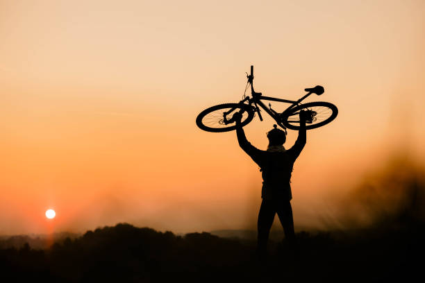 istock Man is holding a bicycle in his hands against the sunset 1356999063