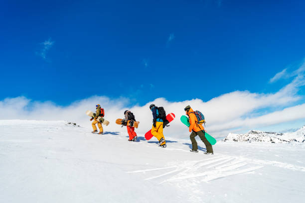 istock Group of snowboarders going up in mountains 1356999096