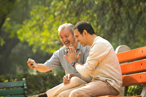 istock Old father and son having fun while using mobile phone at park 1356999244