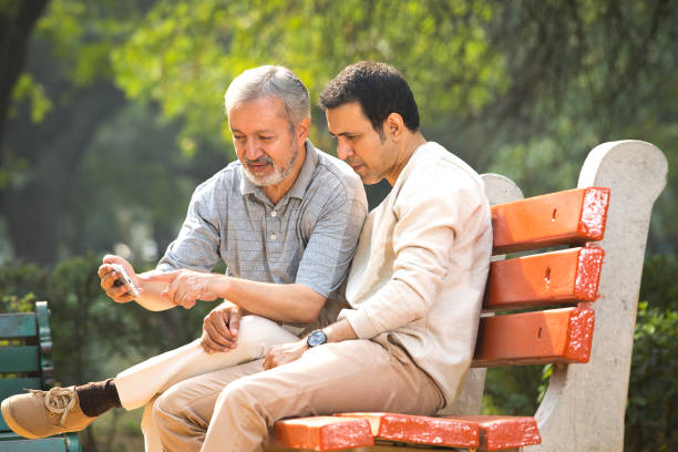 istock Old father and son having fun while using mobile phone at park 1356999283
