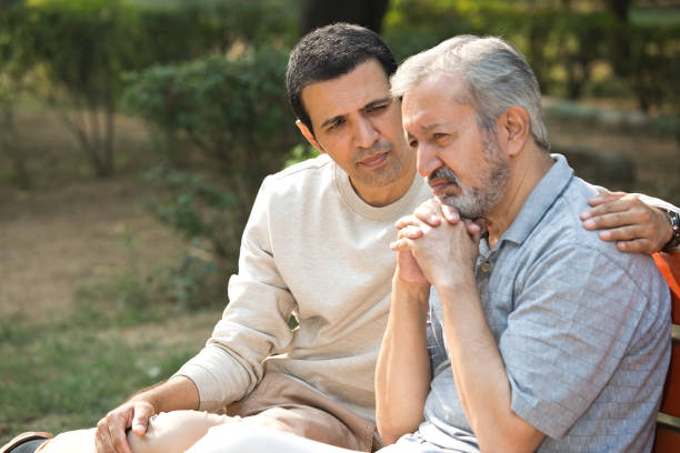 istock Son comforting thoughtful old father at park 1357000343