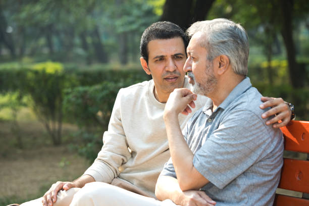 istock Son comforting thoughtful old father at park 1357000386
