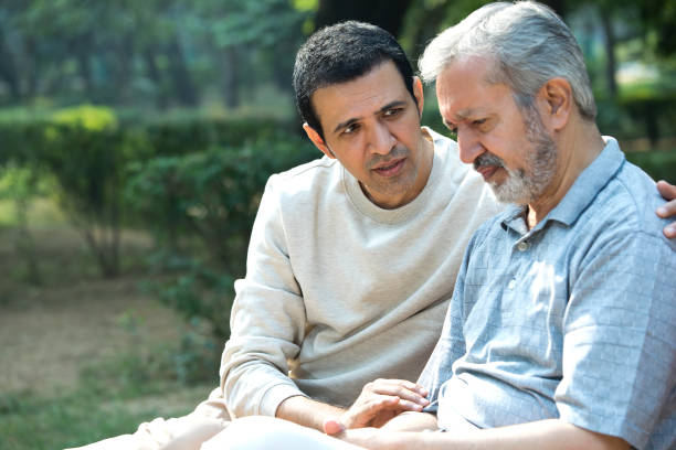 istock Son comforting thoughtful old father at park 1357000403